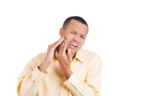 man holding mouth in pain