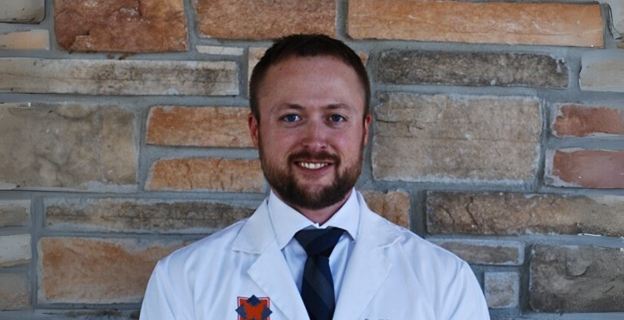 Headshot of Dr Midtling smiling in his white Northwest Oral coat in front of a brick wall