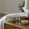Glass of water and soft food beside a folded blanket, representing rest and recovery after oral surgery.