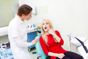 Closeup portrait sad girl, patient woman with painful tooth, ache siting in chair, medical office explaining her problem to dentist doctor isolated dental clinic background. Face expressions, feelings-2