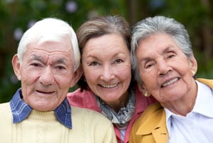 Old couple and their daughter smiling outdoors