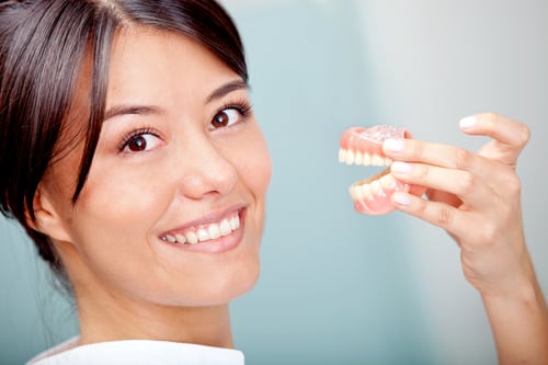 Woman holding a teeth sample or prosthesis at the dentist