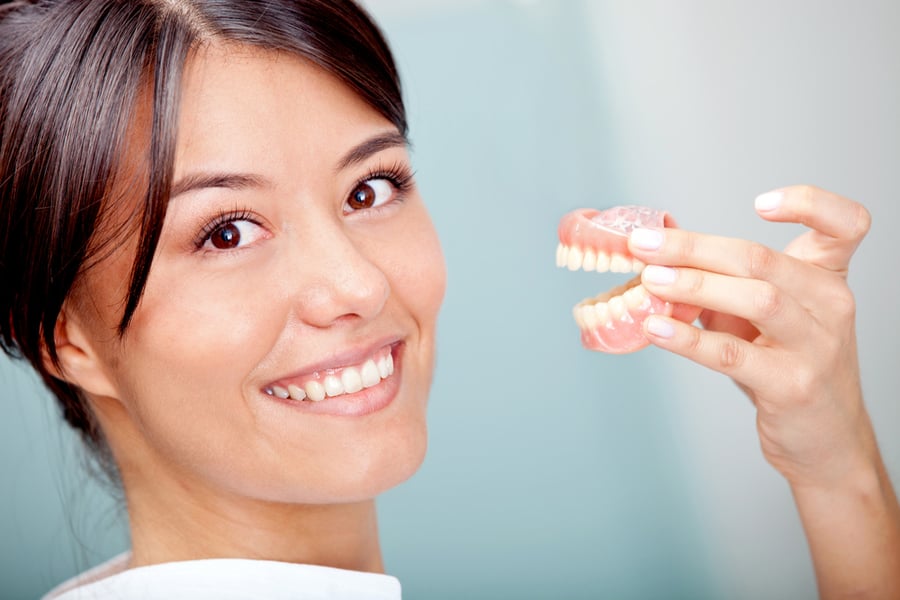 Woman holding a teeth sample or prosthesis at the dentist