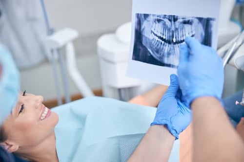 Female dental patient looking at x-ray of her jaw with oral surgeon