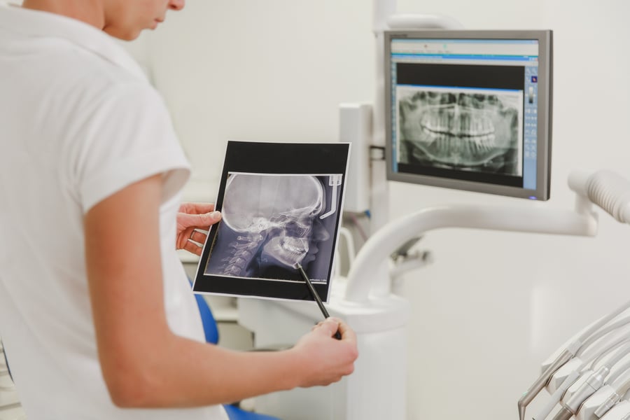 Female dentist holding X-ray photo of a human skull with a picture of a jaw