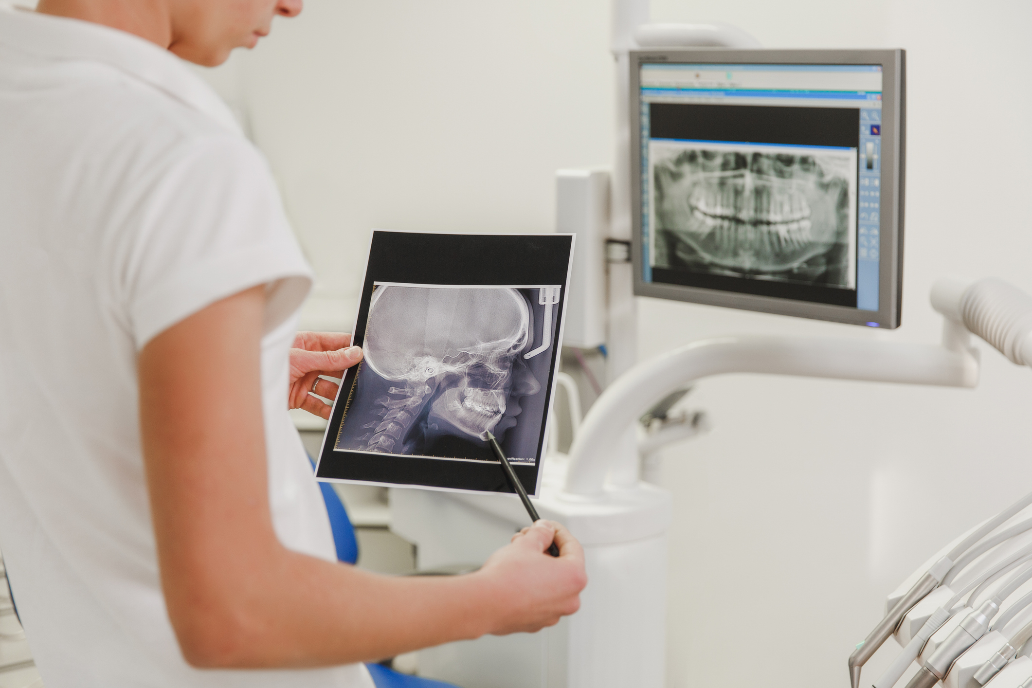 Female dentist holding X-ray photo of a human skull with a picture of a jaw